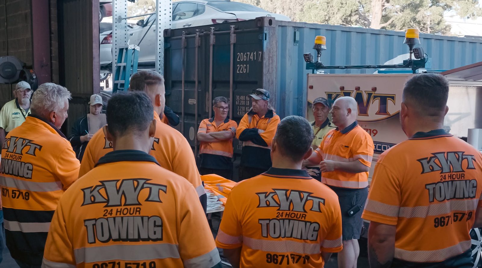 KWT crew gathered beside a shipping container for a briefing