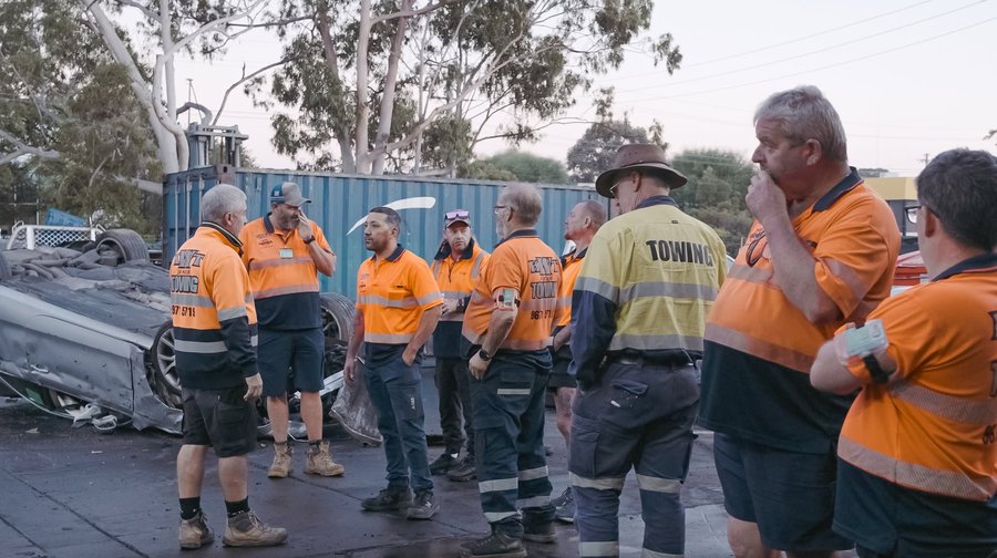 KWT dispatcher taking a call — hi-vis crew briefing at a recovery yard