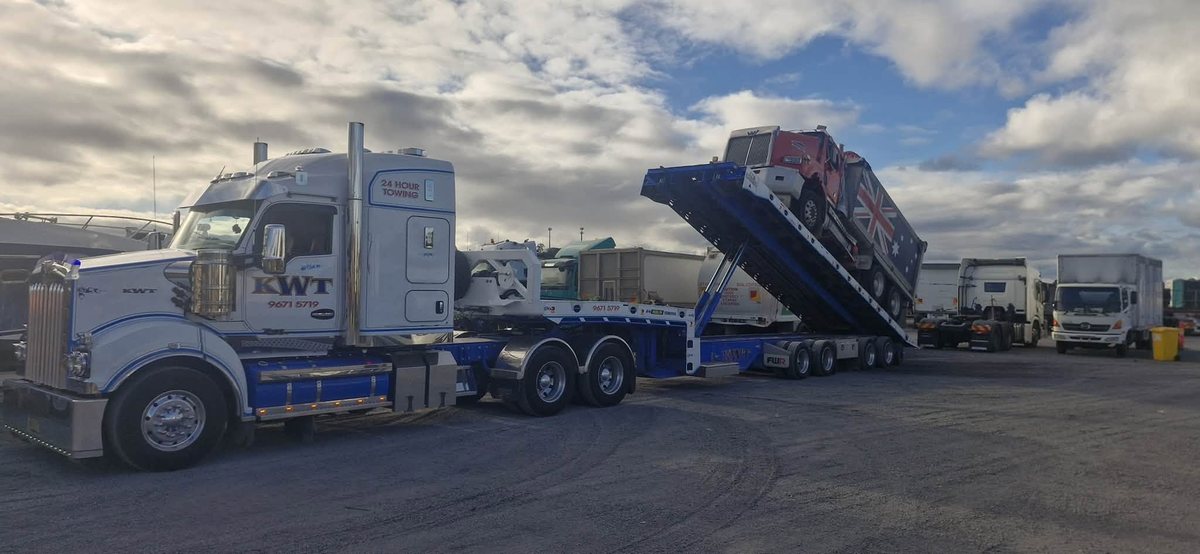 KWT prime mover with heavy machinery loaded on a low loader