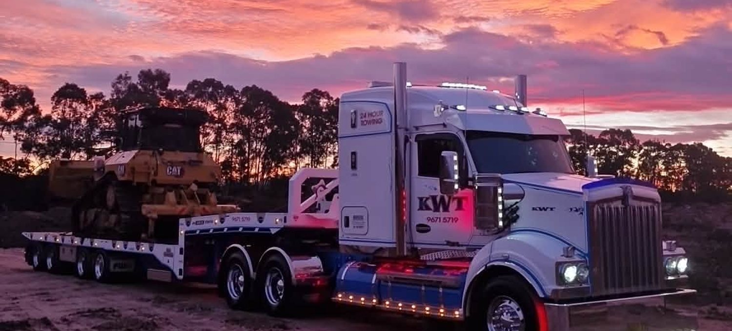 KWT low loader carrying a CAT dozer at sunset