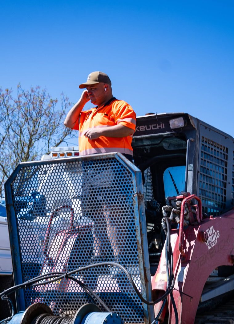 KWT operator loading a compact skid steer onto a truck