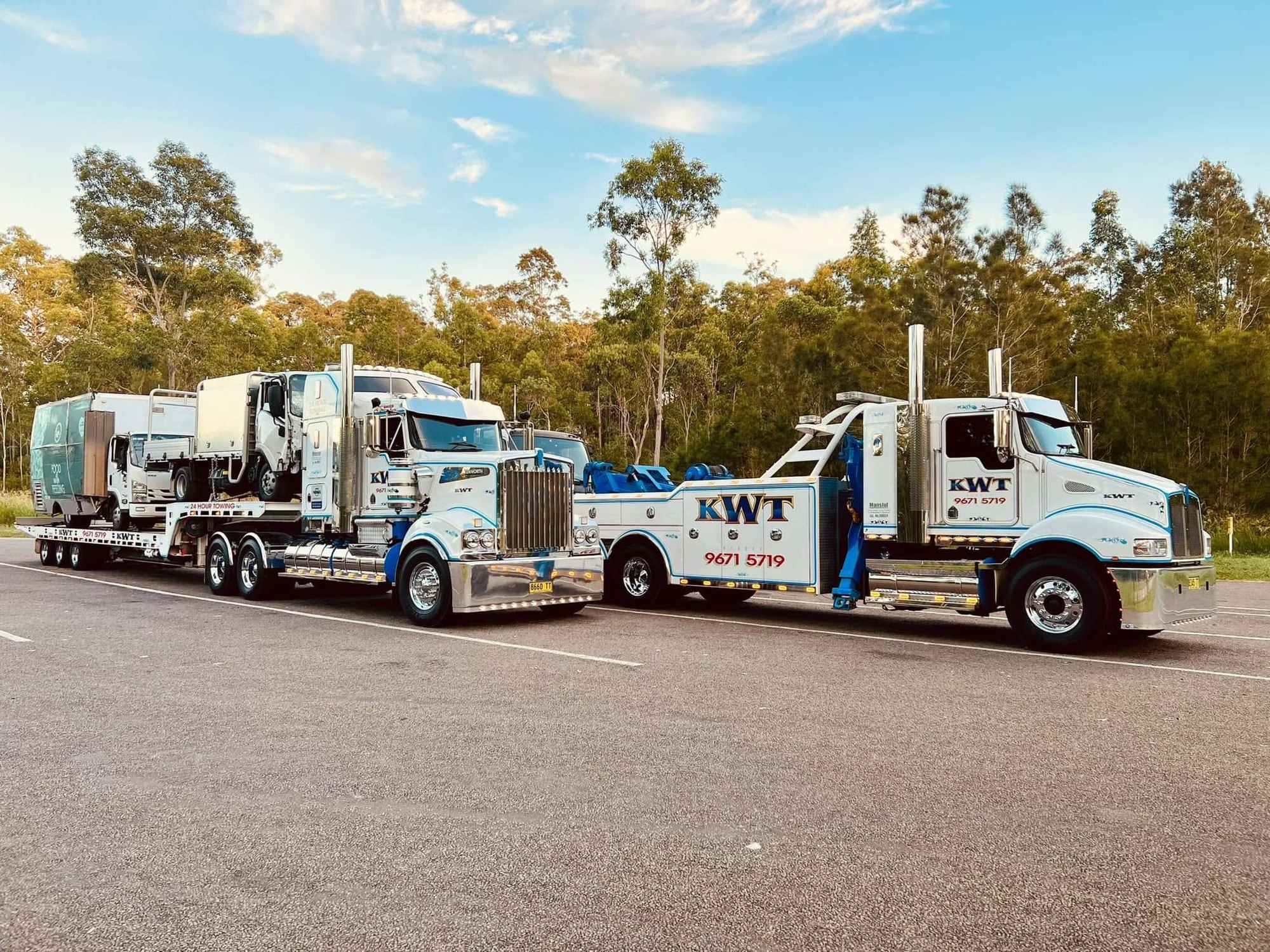 KWT Kenworth prime mover with a loaded low loader alongside a heavy recovery wrecker at golden hour