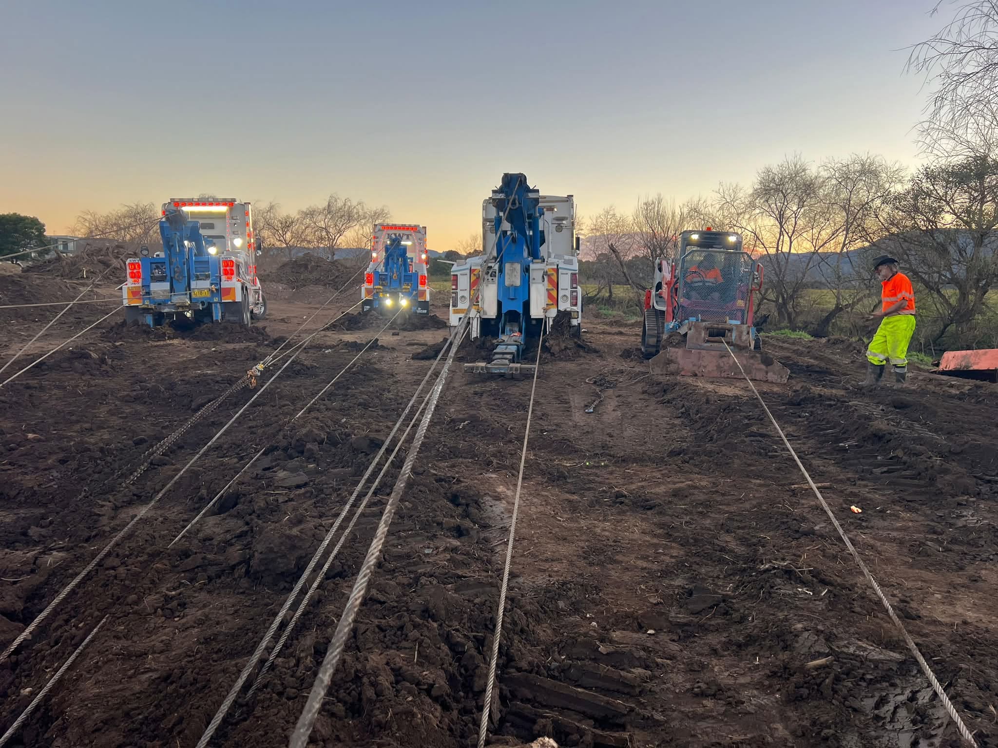 KWT prime mover towing a low loader carrying a wrecked excavator